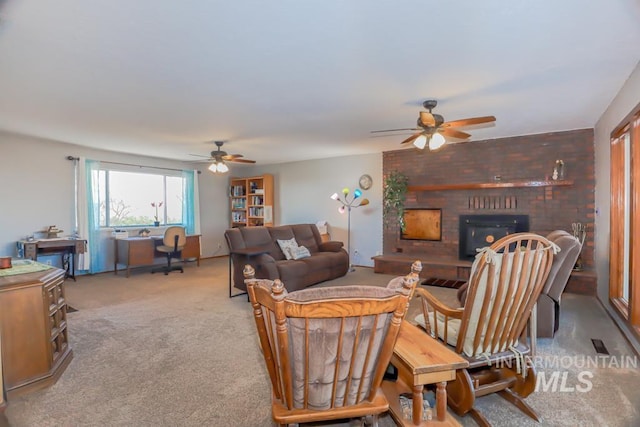 carpeted living room featuring a brick fireplace and ceiling fan