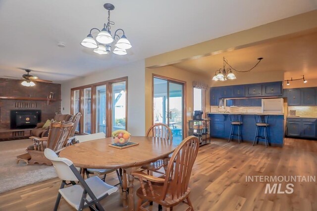 dining space featuring ceiling fan with notable chandelier and wood finished floors