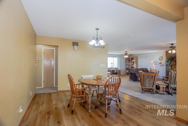 dining area with baseboards, an inviting chandelier, and wood finished floors