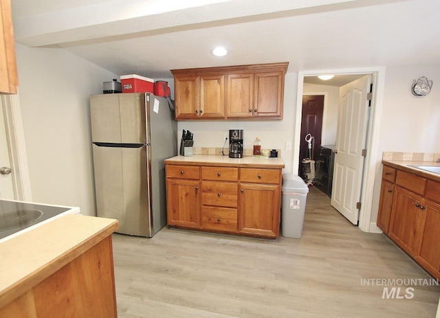 415 S Fern St, Nampa, ID 83686 - kitchen featuring a sink, brown cabinets, light wood-type flooring, light countertops, and freestanding refrigerator