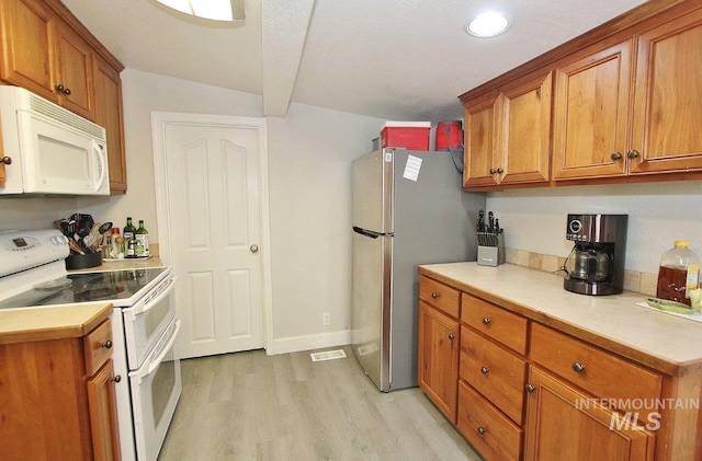 415 S Fern St, Nampa, ID 83686 - kitchen featuring light wood-style flooring, visible vents, white appliances, brown cabinets, and light countertops