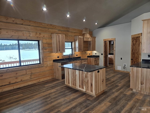 kitchen with light brown cabinets, dark hardwood / wood-style floors, wooden walls, and a center island