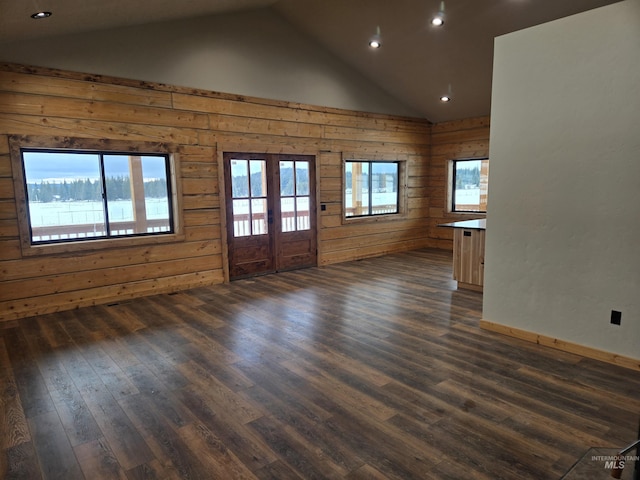 unfurnished living room featuring dark wood-type flooring, vaulted ceiling, french doors, and wooden walls