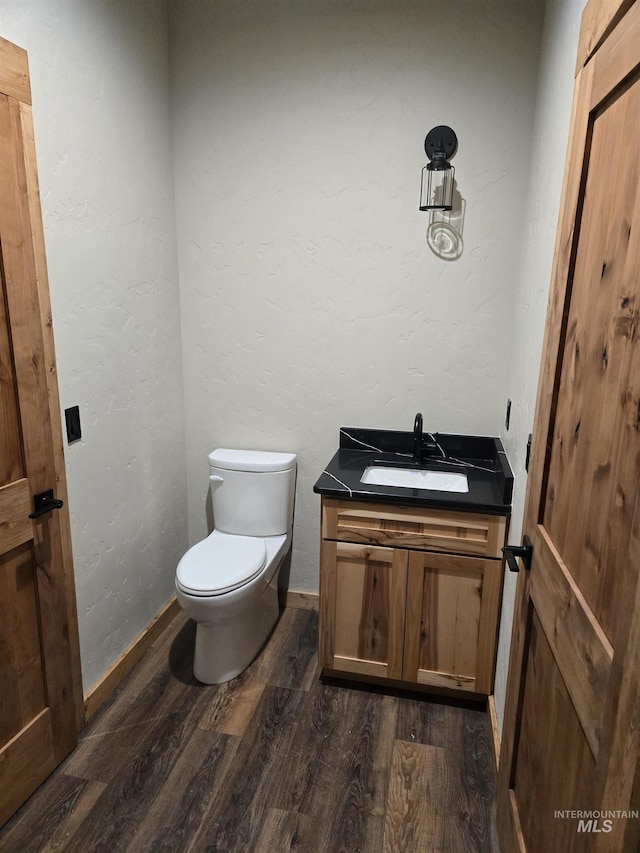 bathroom with toilet, vanity, and wood-type flooring