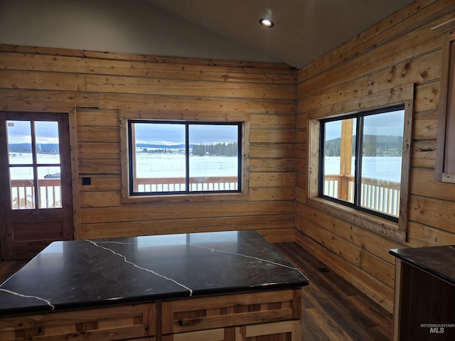 kitchen featuring lofted ceiling, dark stone counters, and wood walls