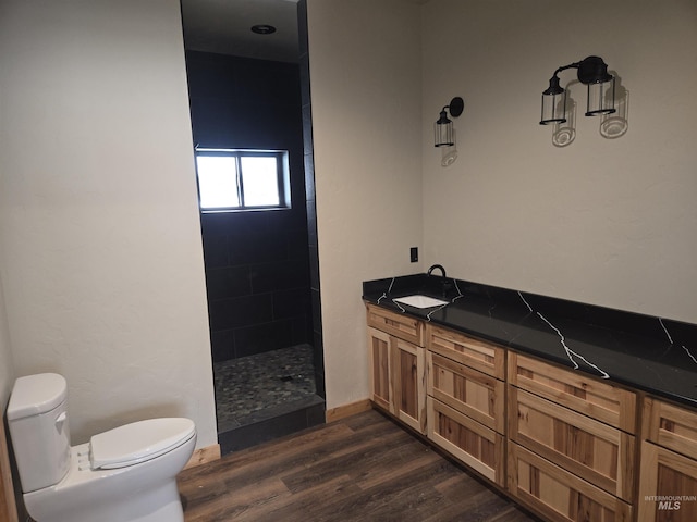 bathroom with toilet, vanity, tiled shower, and hardwood / wood-style flooring