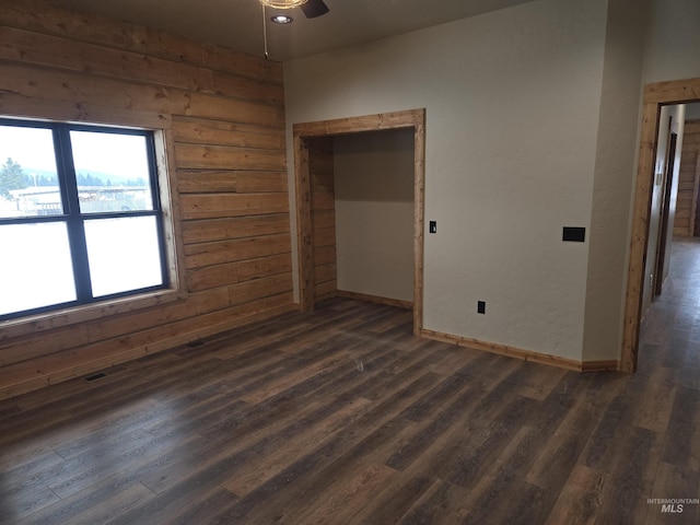 unfurnished room featuring ceiling fan, dark hardwood / wood-style flooring, and wooden walls