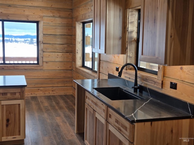 kitchen with dark wood-type flooring, wooden walls, and sink