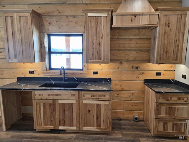 kitchen featuring dark hardwood / wood-style floors, wooden walls, and sink