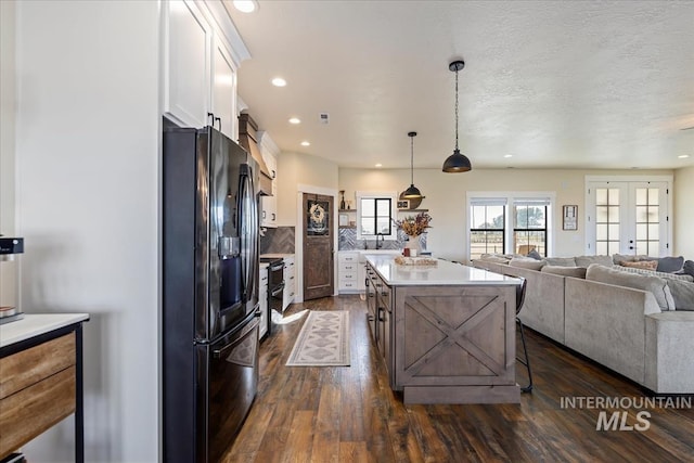 2442 W Market Rd, Homedale, ID 83628 - kitchen featuring white cabinets, light countertops, a center island, dark wood-style floors, and black fridge with ice dispenser