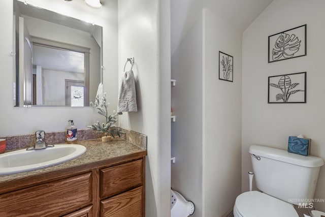 bathroom featuring vanity, toilet, and lofted ceiling