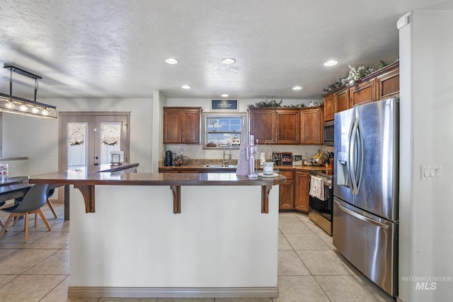 kitchen with a kitchen breakfast bar, sink, hanging light fixtures, light tile patterned flooring, and stainless steel appliances