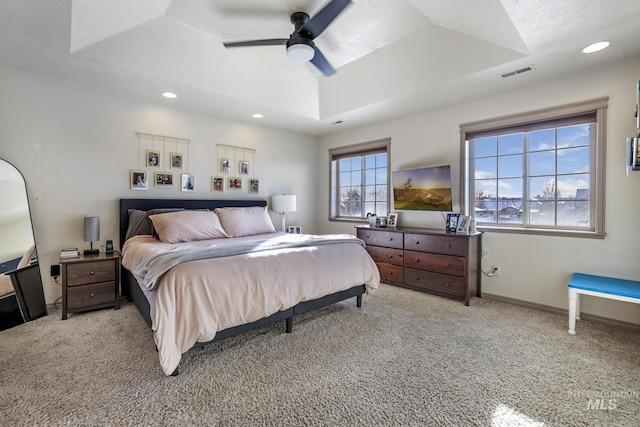 carpeted bedroom featuring ceiling fan and a tray ceiling