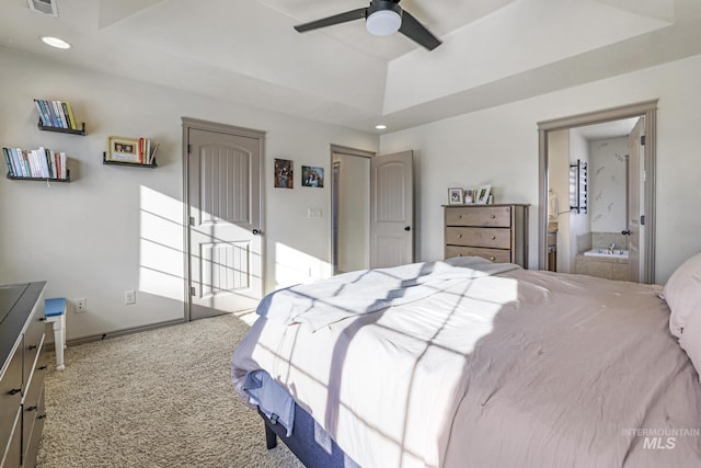 carpeted bedroom featuring a tray ceiling, ceiling fan, and ensuite bathroom