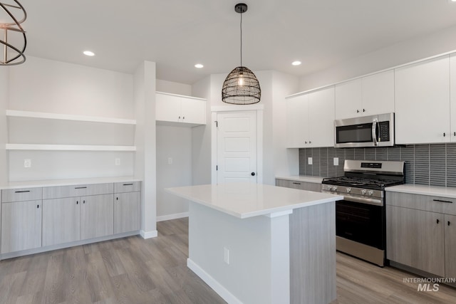 kitchen featuring white cabinetry, hanging light fixtures, appliances with stainless steel finishes, light countertops, and open shelves