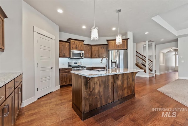 15343 Moss Creek Way, Caldwell, ID 83607 - kitchen featuring stainless steel appliances, a sink, arched walkways, tasteful backsplash, and light stone counters
