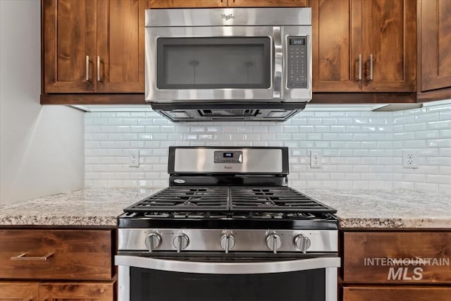 15343 Moss Creek Way, Caldwell, ID 83607 - kitchen featuring stainless steel appliances, decorative backsplash, and light stone countertops