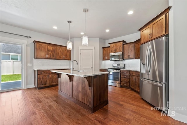 15343 Moss Creek Way, Caldwell, ID 83607 - kitchen with appliances with stainless steel finishes, dark wood finished floors, backsplash, a kitchen island with sink, and recessed lighting