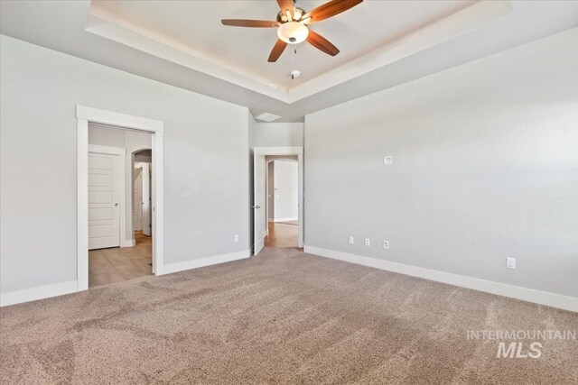 15343 Moss Creek Way, Caldwell, ID 83607 - unfurnished bedroom with light colored carpet, a tray ceiling, baseboards, and ceiling fan