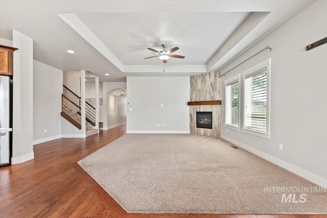 15343 Moss Creek Way, Caldwell, ID 83607 - unfurnished living room with a tray ceiling, stairs, ceiling fan, a fireplace, and arched walkways