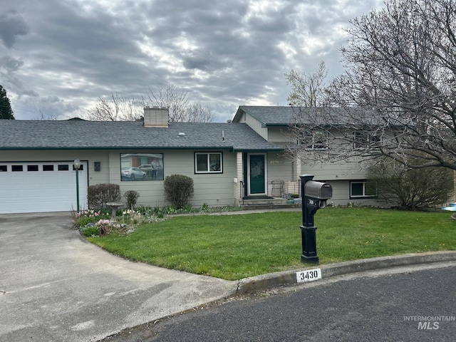 split level home featuring a garage, a front yard, a chimney, a shingled roof, and concrete driveway