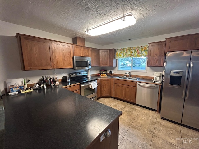 kitchen featuring dark countertops, a sink, a textured ceiling, and stainless steel appliances