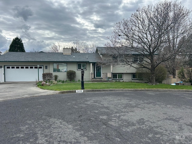 view of front facade with a chimney, a garage, driveway, and a front lawn