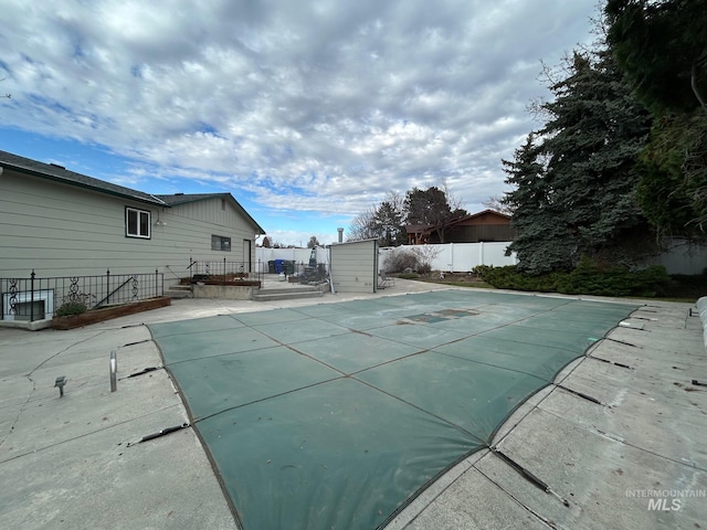 view of pool featuring an outbuilding, a storage shed, a fenced backyard, a patio, and a fenced in pool