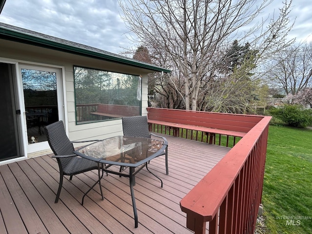 wooden deck featuring outdoor dining area and a lawn
