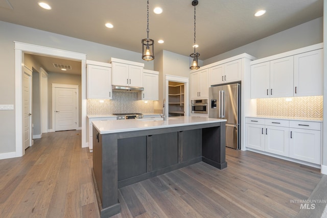 kitchen with visible vents, a sink, under cabinet range hood, appliances with stainless steel finishes, and light countertops