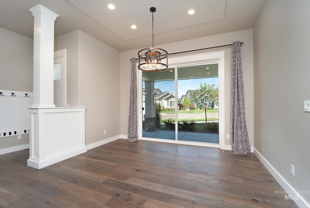 unfurnished dining area with dark wood-type flooring, baseboards, and ornate columns