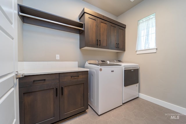 laundry room featuring light tile patterned floors, cabinet space, washer and dryer, and baseboards