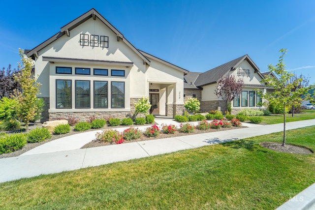 view of front of home featuring a front yard, stone siding, and stucco siding