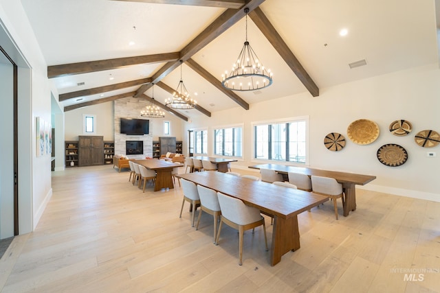 dining space featuring visible vents, light wood finished floors, high vaulted ceiling, beam ceiling, and a fireplace