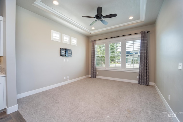 carpeted spare room featuring a ceiling fan, a tray ceiling, recessed lighting, and baseboards