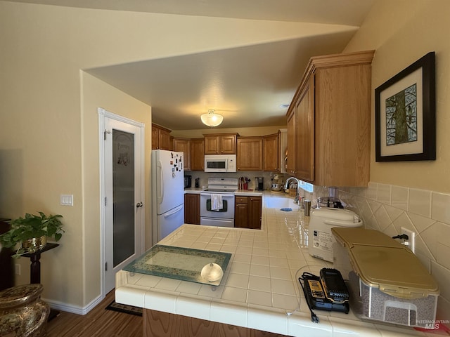 1053 Caswell Ave W, Twin Falls, ID 83301 - kitchen with white appliances, tile countertops, a sink, a peninsula, and brown cabinetry