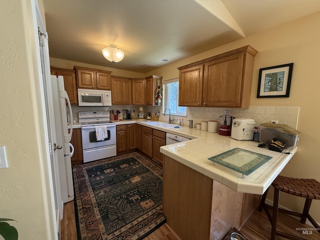 1053 Caswell Ave W, Twin Falls, ID 83301 - kitchen with white appliances, a sink, a peninsula, and brown cabinetry