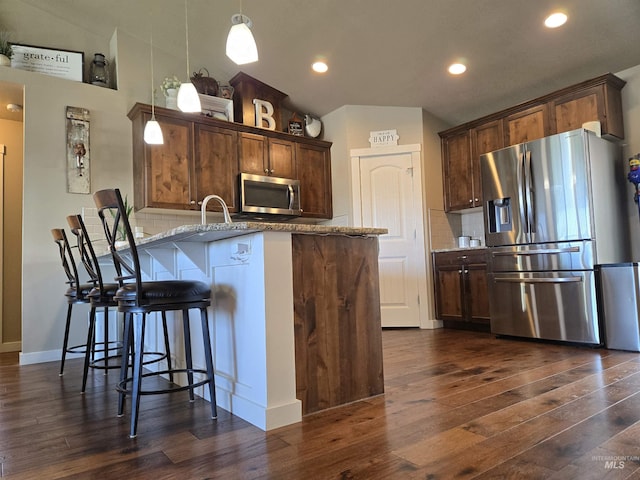 235 Meadow View Dr, Payette, ID 83661 - kitchen with appliances with stainless steel finishes, dark wood-style floors, backsplash, a peninsula, and a kitchen breakfast bar
