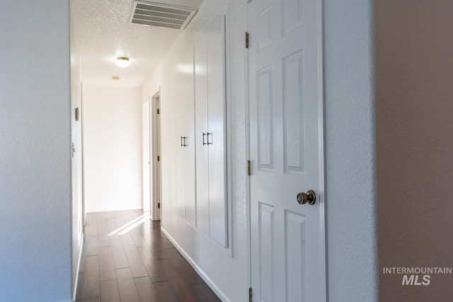 hallway featuring a textured ceiling and dark hardwood / wood-style flooring