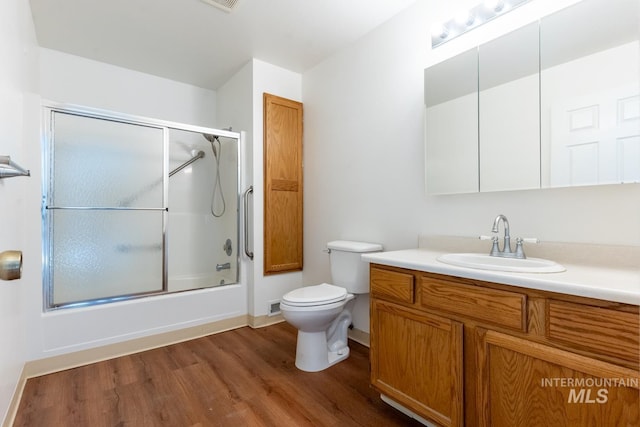 full bathroom featuring enclosed tub / shower combo, hardwood / wood-style floors, vanity, and toilet