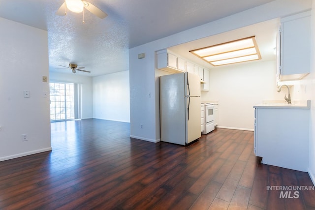 kitchen with white appliances, white cabinetry, sink, and a textured ceiling