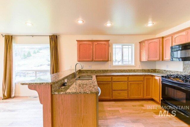 1962 E 6th St, Moscow, ID 83843 - kitchen featuring a peninsula, light wood-type flooring, stone counters, black appliances, and a sink