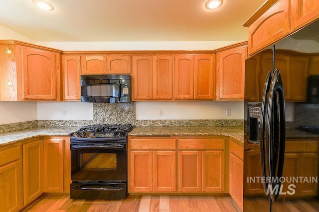 1962 E 6th St, Moscow, ID 83843 - kitchen featuring brown cabinetry, light stone countertops, light wood-style flooring, and black appliances