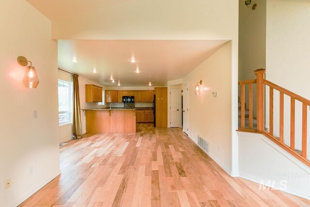 1962 E 6th St, Moscow, ID 83843 - kitchen featuring visible vents, light wood-style floors, a peninsula, black microwave, and brown cabinetry