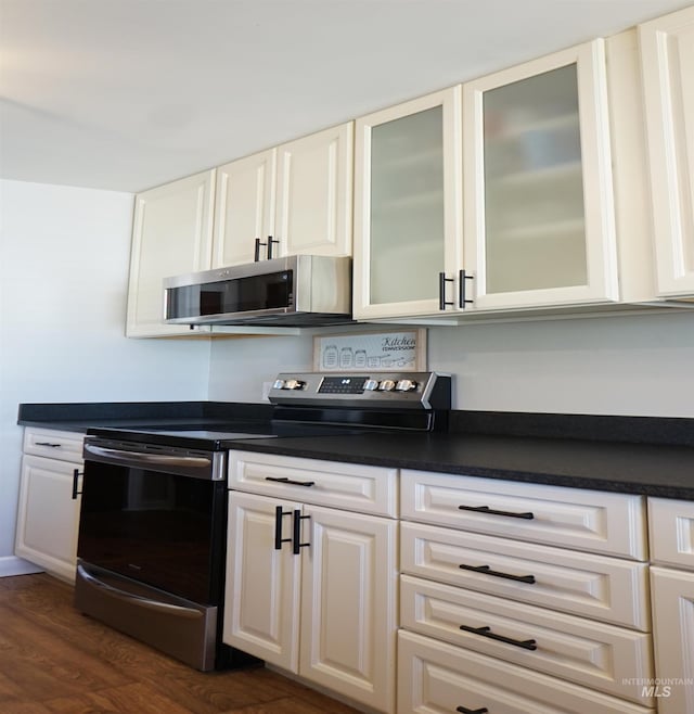 kitchen with dark wood-type flooring, appliances with stainless steel finishes, and white cabinets