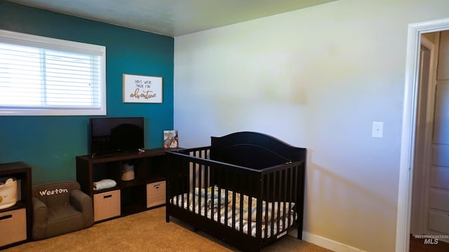 bedroom with a nursery area and light colored carpet