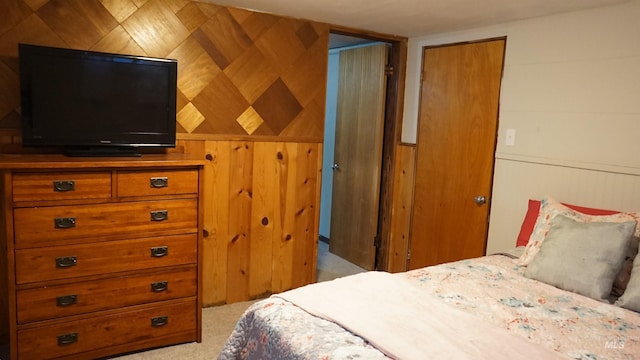 carpeted bedroom with a closet and wood walls