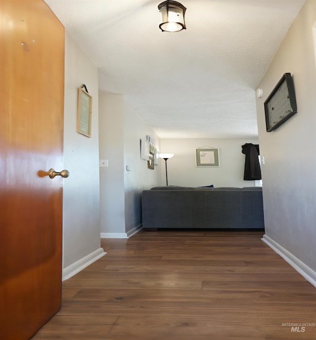 corridor with a textured ceiling and dark hardwood / wood-style floors