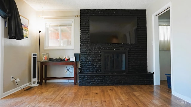 living room featuring wood-type flooring, a textured ceiling, and a fireplace