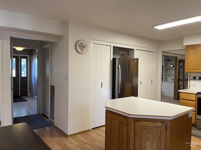 354 W Syringa Ct, Lewiston, ID 83501 - kitchen featuring freestanding refrigerator, light countertops, light wood finished floors, brown cabinetry, and a center island